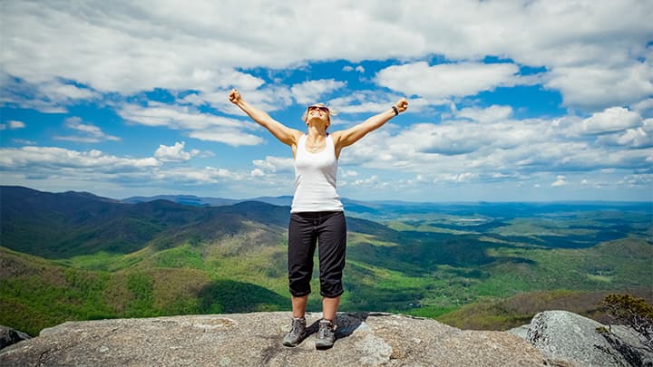 Happy woman reaching the top of a mountain