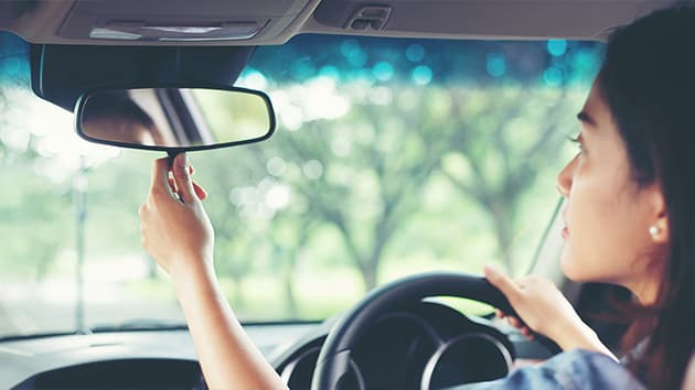 Young driver adjusting a rear view mirror
