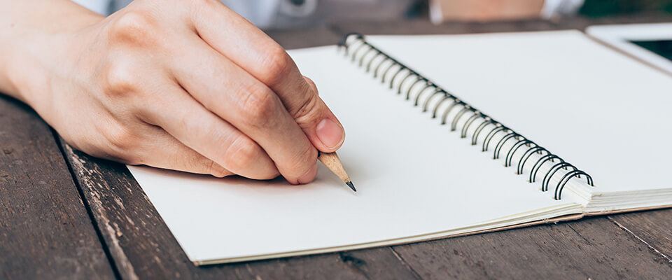 Woman writing in notebook with pencil