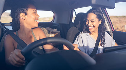 Two happy women driving in a car